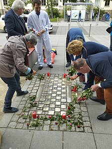 DGU verlegt Stolpersteine Mai 2023 © J. Arndt / DGU Menschen legen Blumen um Stolpersteine