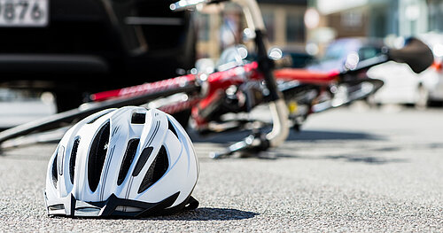 Fahrradhelm und umgestürztes Fahrrad auf der Straße nach Unfall