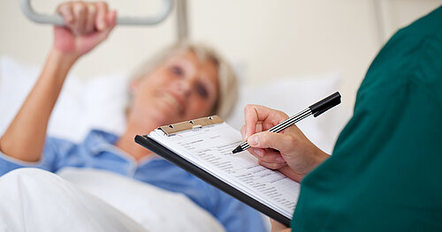 Krankenschwester nimmt in Krankenzimmer Patientendaten auf