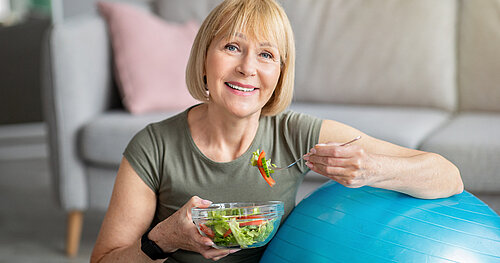 Ältere Frau isst Salat nach Sport