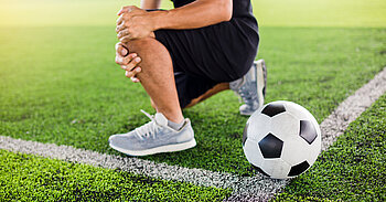 Fußballspieler hält sich Knie am Rand des Fußballfeldes